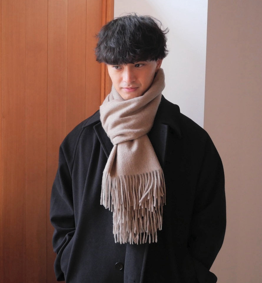 モカブラウンのストールを黒いコートに合わせた着用例。首元の巻き方とフリンジ