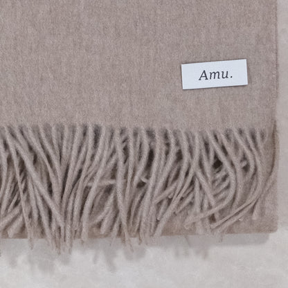 モカブラウンのカシミヤ生地とフリンジ、Amu.の織りネームの接写
